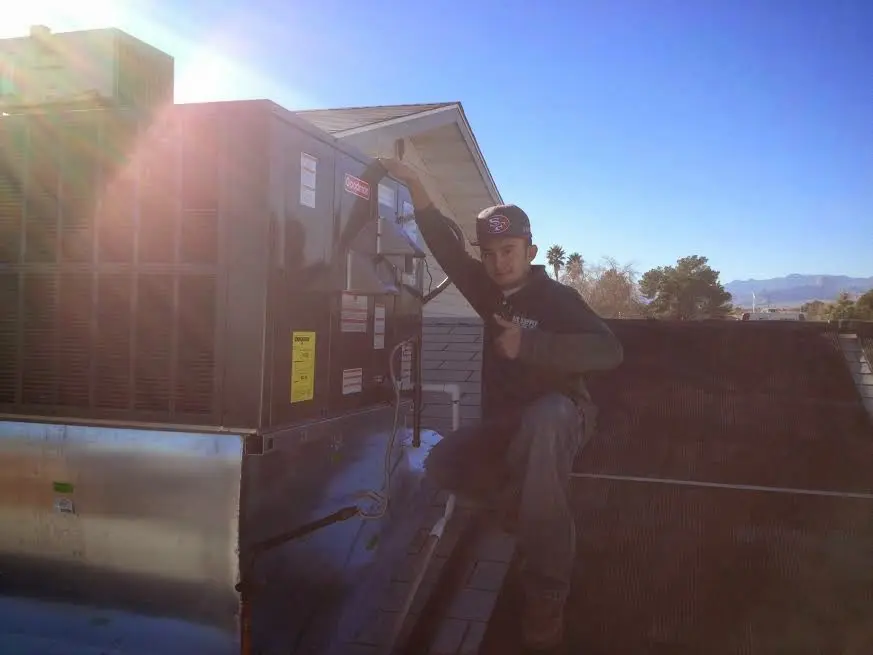 HVAC technician performing AC Tune-Up on a rooftop unit in Belle Chasse